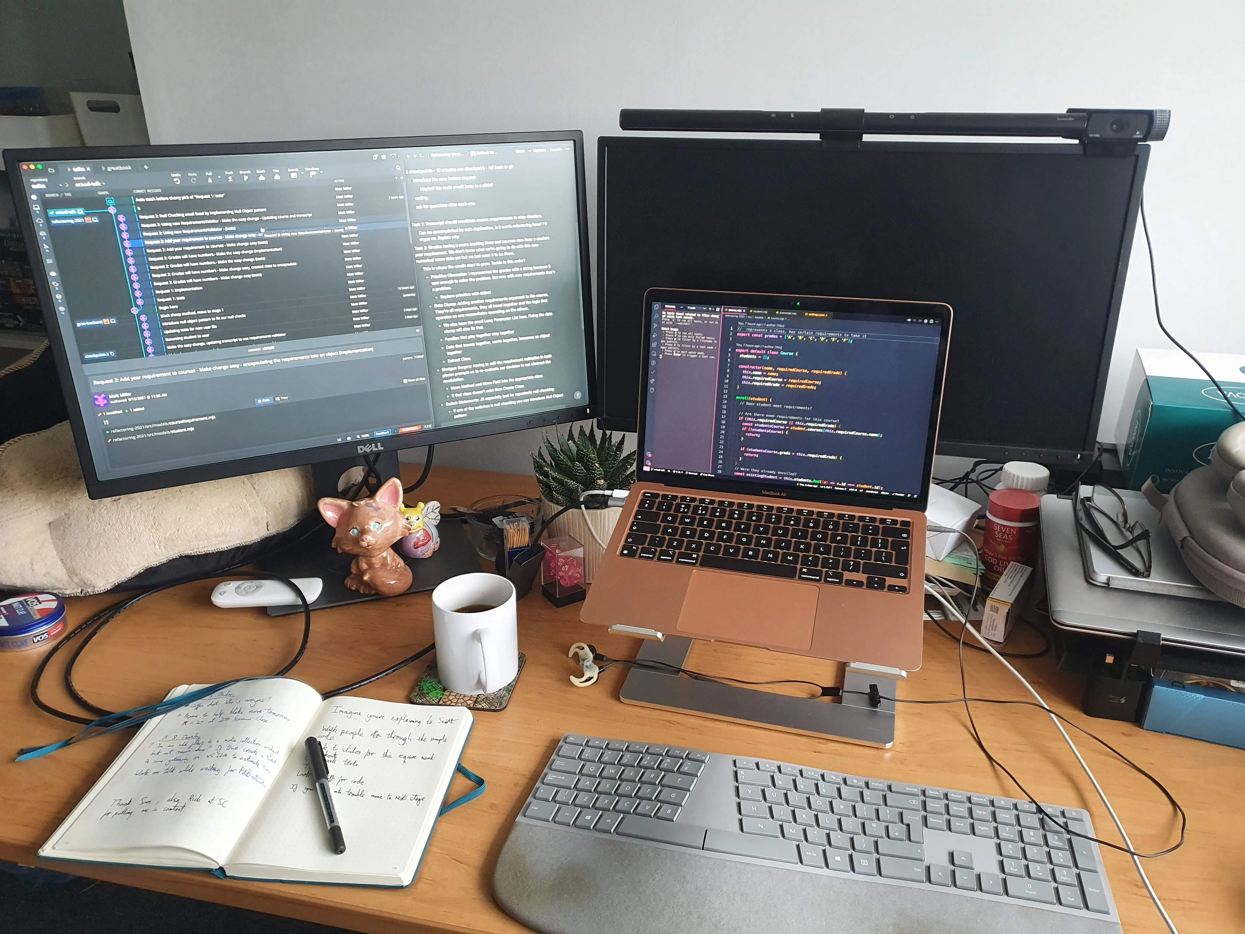 Image of my desk, comprising my macbook, 2 screens, a keyboard and various clutter