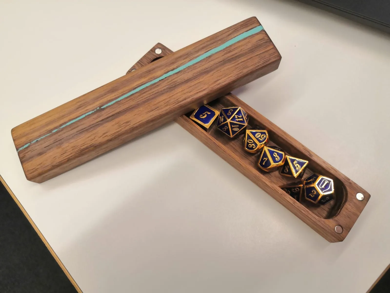 My favourite dice and their custom box, courtesy of my friend. Image of some metallic blue dice inside a walnut box with pale blue resin filling gaps.